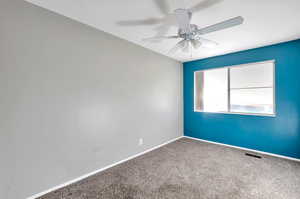 Carpeted spare room featuring ceiling fan