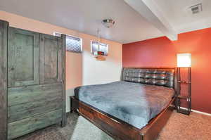 Carpeted bedroom featuring beamed ceiling