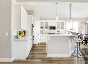 Kitchen featuring white cabinets, dark hardwood / wood-style floors, stainless steel appliances, and hanging light fixtures