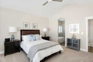 Bedroom with ensuite bath, ceiling fan, carpet floors, and lofted ceiling