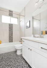 Full bathroom featuring vanity, tiled shower / bath combo, and toilet