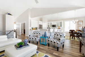 Living room featuring hardwood / wood-style flooring, high vaulted ceiling, and a notable chandelier