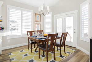 Dining space featuring hardwood / wood-style floors, lofted ceiling, a wealth of natural light, and an inviting chandelier