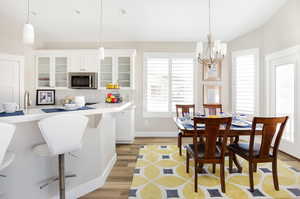 Dining area with light hardwood / wood-style flooring, a chandelier, and vaulted ceiling