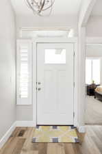 Foyer with light wood-type flooring and an inviting chandelier