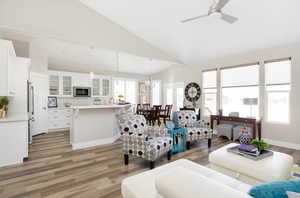 Living room with hardwood / wood-style floors, high vaulted ceiling, and ceiling fan