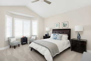 Carpeted bedroom with ceiling fan and lofted ceiling