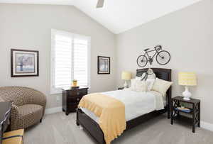 Carpeted bedroom featuring vaulted ceiling and ceiling fan