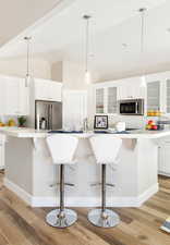 Kitchen featuring white cabinetry, light hardwood / wood-style flooring, a spacious island, decorative backsplash, and appliances with stainless steel finishes