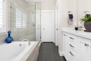 Bathroom featuring tile patterned floors, vanity, and separate shower and tub