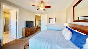 Carpeted bedroom featuring connected bathroom and ceiling fan