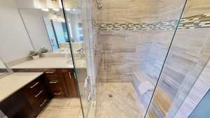 Bathroom with tile patterned floors, a shower with door, and vanity