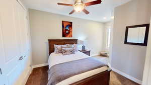 Carpeted bedroom featuring ceiling fan and a closet