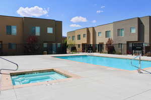 View of swimming pool with a patio and a hot tub