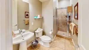 Bathroom with tile patterned floors, toilet, a shower with shower door, and sink