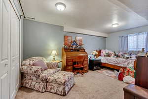 Carpeted bedroom featuring a textured ceiling and a closet