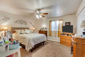 Carpeted bedroom with ceiling fan and a closet