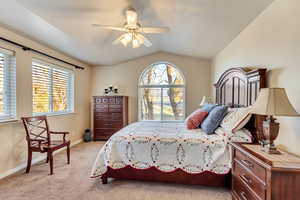 Bedroom featuring ceiling fan, light carpet, and lofted ceiling