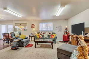 Living room with ceiling fan, a textured ceiling, and hardwood / wood-style flooring