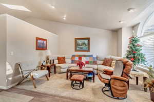 Living room with lofted ceiling with skylight and light hardwood / wood-style flooring