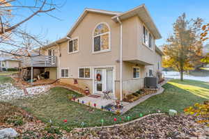 Rear view of property featuring a yard, central AC, and a wooden deck