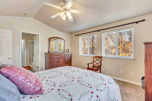 Carpeted bedroom featuring ceiling fan and lofted ceiling