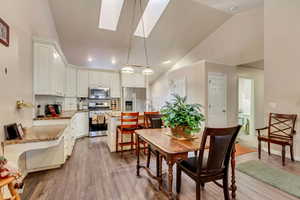 Dining room with a skylight, high vaulted ceiling, and hardwood / wood-style flooring