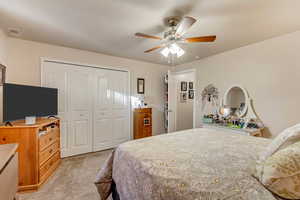 Bedroom with light carpet, a closet, and ceiling fan