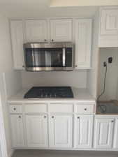 Kitchen featuring white cabinets and gas stovetop