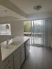 Kitchen featuring sink, stainless steel dishwasher, decorative light fixtures, and light hardwood / wood-style floors