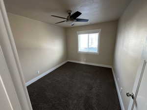 Carpeted empty room featuring ceiling fan