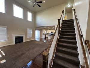 Stairway featuring carpet flooring, a high ceiling, and ceiling fan