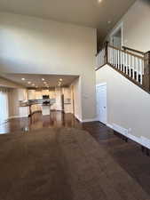 Unfurnished living room featuring dark hardwood / wood-style flooring and a high ceiling