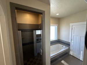 Bathroom with tile patterned floors, separate shower and tub, and a textured ceiling