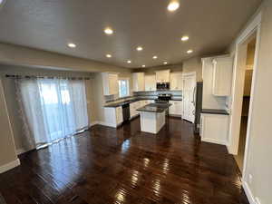 Kitchen featuring white cabinets, appliances with stainless steel finishes, a kitchen island, and a wealth of natural light