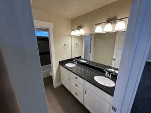 Bathroom with tile patterned floors, vanity, toilet, and a textured ceiling