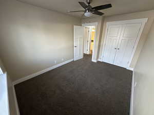 Unfurnished bedroom featuring ceiling fan, a closet, and dark colored carpet