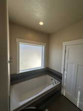 Bathroom featuring a bathtub, a textured ceiling, and tile patterned flooring