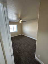 Carpeted empty room with a textured ceiling and ceiling fan