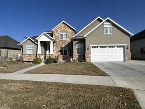 Craftsman inspired home featuring a garage and a front lawn