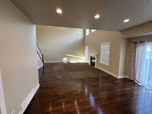 Unfurnished living room featuring dark hardwood / wood-style flooring and lofted ceiling