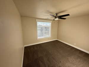 Carpeted spare room with ceiling fan and a textured ceiling