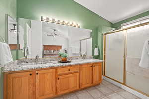 Bathroom with an enclosed shower, vanity, ceiling fan, tile patterned flooring, and lofted ceiling