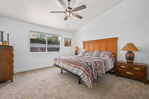 Bedroom featuring ceiling fan, light carpet, and vaulted ceiling