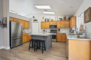 Kitchen featuring a kitchen bar, stainless steel appliances, vaulted ceiling, sink, and a center island