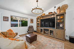 Living room featuring hardwood / wood-style floors, a chandelier, and vaulted ceiling