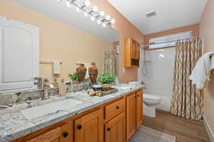 Full bathroom with vanity, toilet, wood-type flooring, and shower / tub combo with curtain