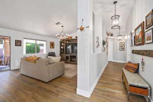 Living room with hardwood / wood-style floors, lofted ceiling, and an inviting chandelier