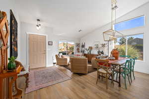 Dining space featuring a notable chandelier, light hardwood / wood-style floors, and vaulted ceiling