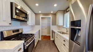 Kitchen featuring sink, decorative backsplash, light stone counters, dark hardwood / wood-style flooring, and stainless steel appliances